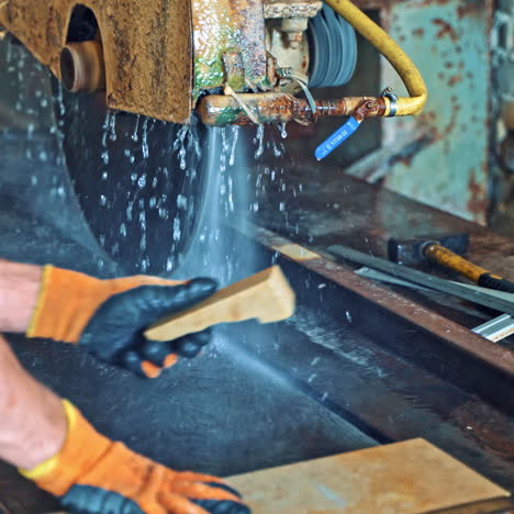 automated circular saw cuts the stone slab at industrial factory. process of cutting stone stove with water. worker controls the electric cutter machine.