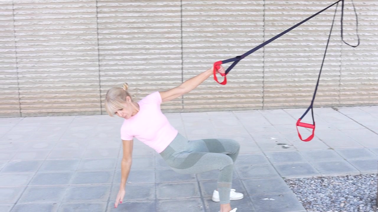 A woman exercising with resistance bands in a park staying active and engaging in outdoor fitness