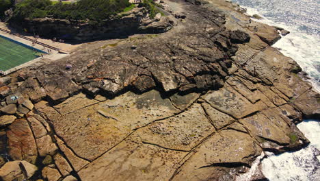 Drone-skimming-rocks-then-ascending-to-ocean-views-swimming-pool-cars-and-people-Ocean-and-sea-stock-videos