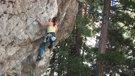 mediumshot of a rock climber making her way up a sheer granite cliff face