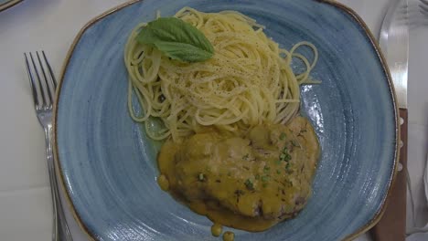 beef tenderloin medallion in mustard sauce accompanied by spaghetti al burro with pepper and spearmint leaf