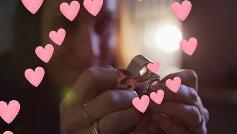 animación de los corazones sobre la mujer caucásica inspeccionando el anillo