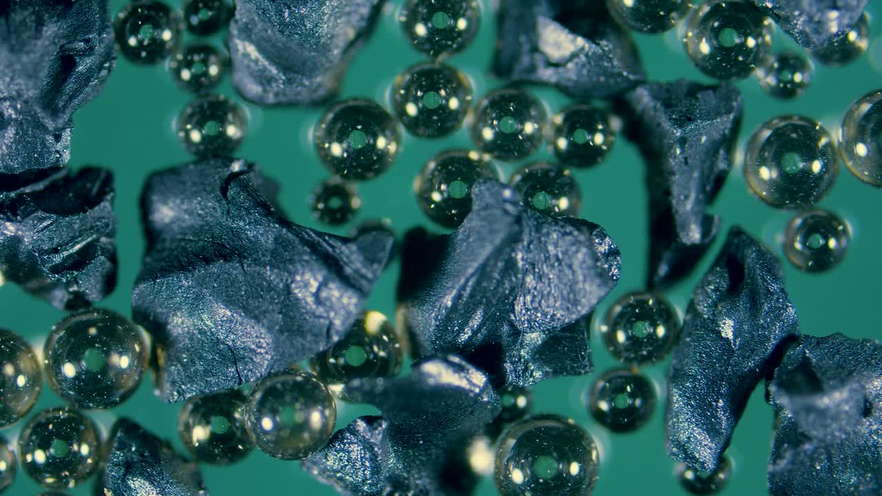 Ion-exchange resin beads in water filter between activated charcoal granules under microscope