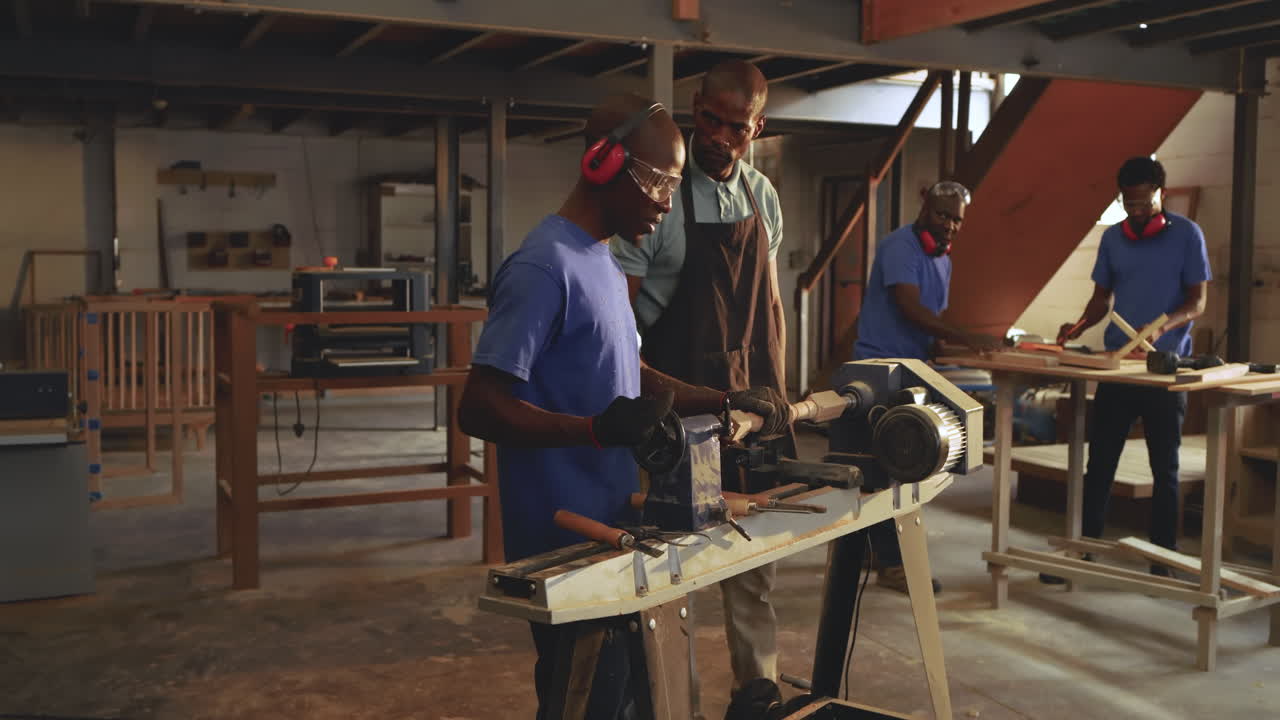 At workshop start instructor guiding apprentice shaping blank on lathe in woodshop to master skills