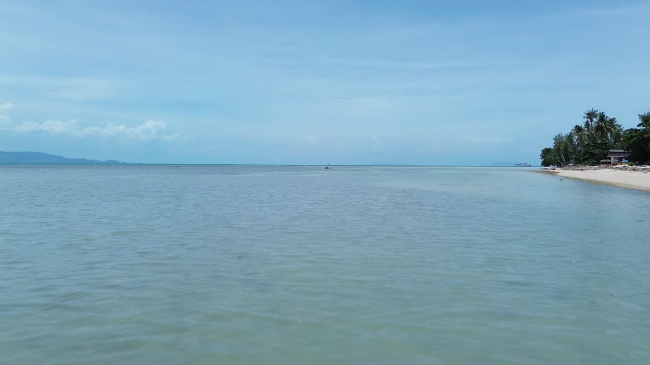 Aerial footage of Thong Sala Beach with a wide sandy shoreline, turquoise sea and lush tropical scenery on Koh Phangan island, Thailand