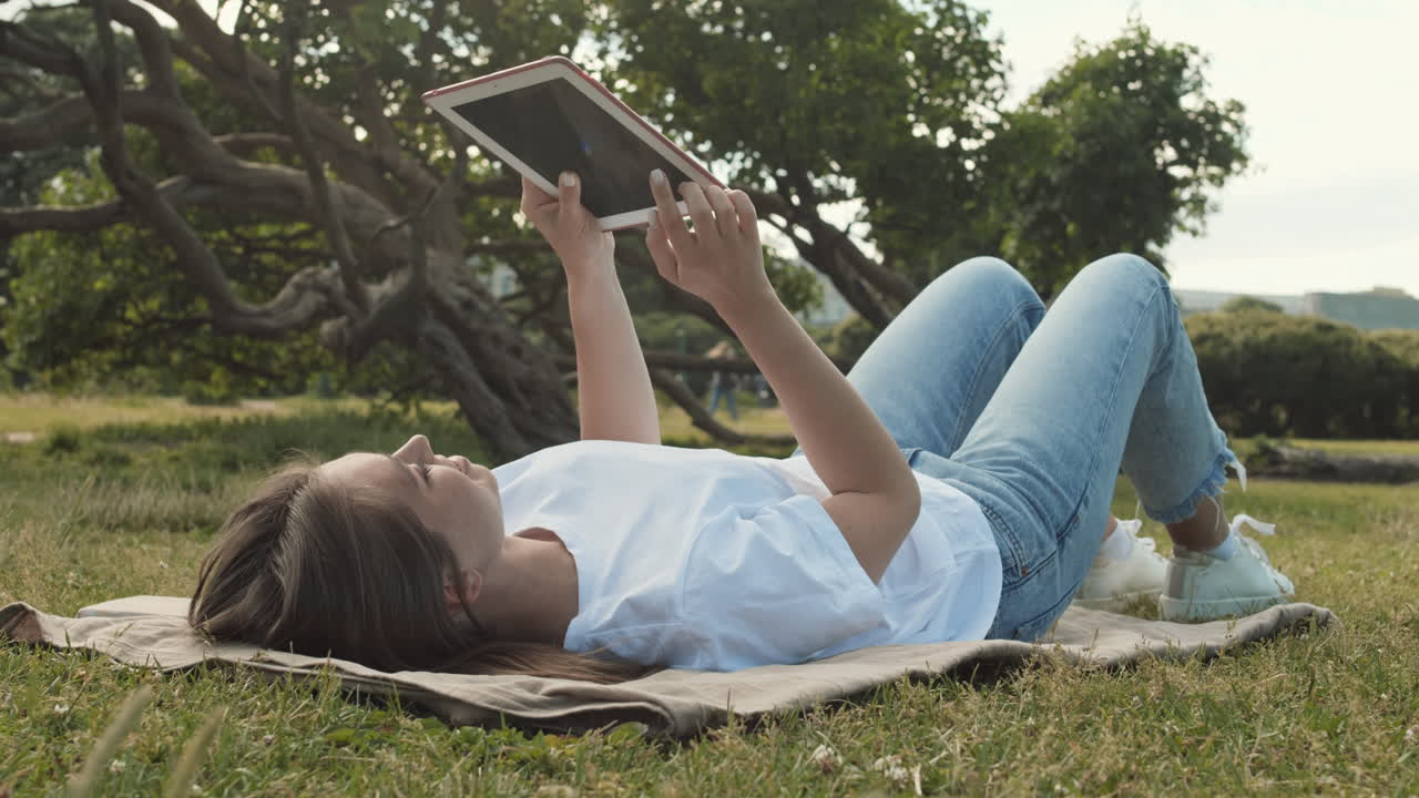 Woman Using Tablet Lying on Lawn