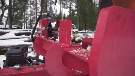 man splitting log on log splitter for firewood in winter