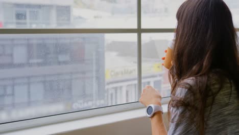 Geschäftsfrau-Trinkt-Kaffee,-Während-Sie-Am-Fenster-Im-Büro-Sitzt-4k