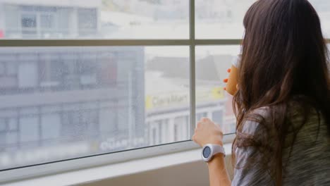 mujer de negocios bebiendo café mientras estaba sentada cerca de la ventana en la oficina 4k
