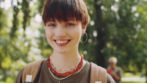 Portrait-of-Cheerful-College-Girl-in-Park