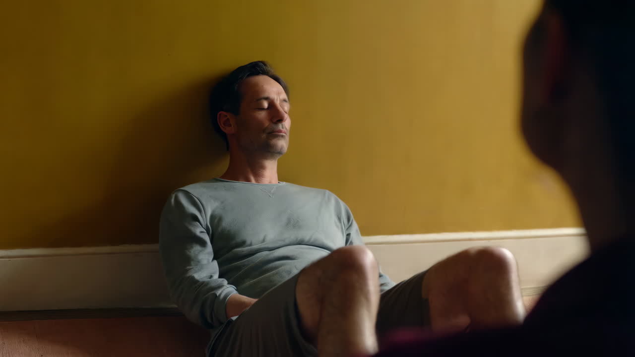 Man relaxing peacefully against a yellow wall