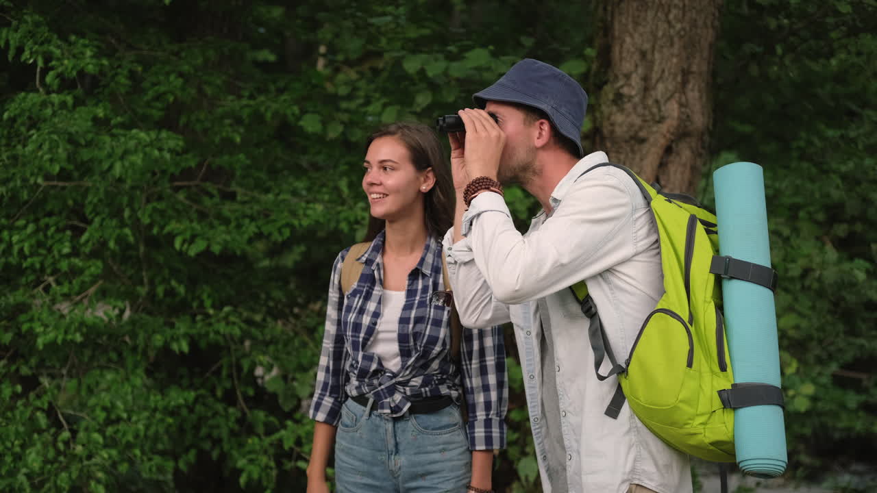 пара, гуляющая и исследующая лес с помощью бинокля