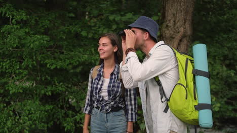 pareja caminando y explorando el bosque con binoculares