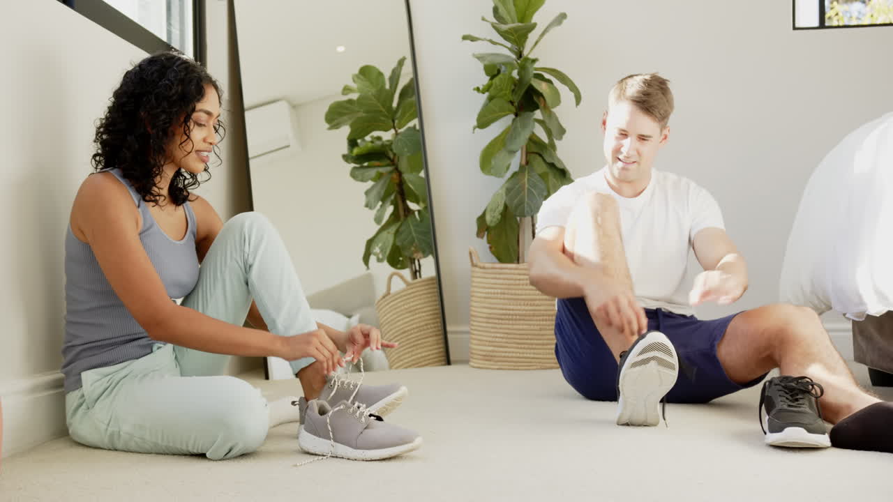 Putting on sneakers, young multiracial couple getting ready for workout at home