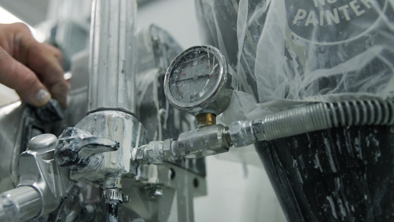 Close-up of a pressure gauge needle increasing on a paint sprayer, ideal for industrial, construction, manufacturing, and equipment operation visuals.