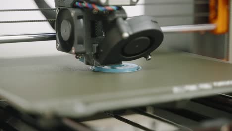 GRADED,-Close-shot,-3D-printer-prints-the-base-for-blue-sprocket-white-room-laboratory