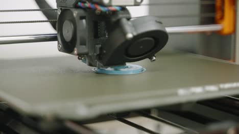 graduado, tiro de cerca, impresora 3d imprime la base para la rueda dentada azul sala de laboratorio blanca