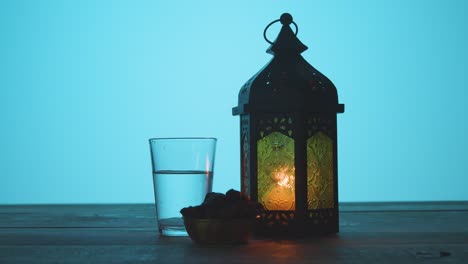 Tracking-Shot-of-Lantern-Water-and-Dates-On-a-Table-During-Dusk-