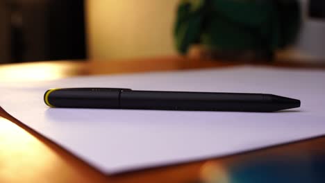 black-pen-is-placed-on-a-desk-with-white-paper-and-grabbed-and-taken-away-by-one-hand