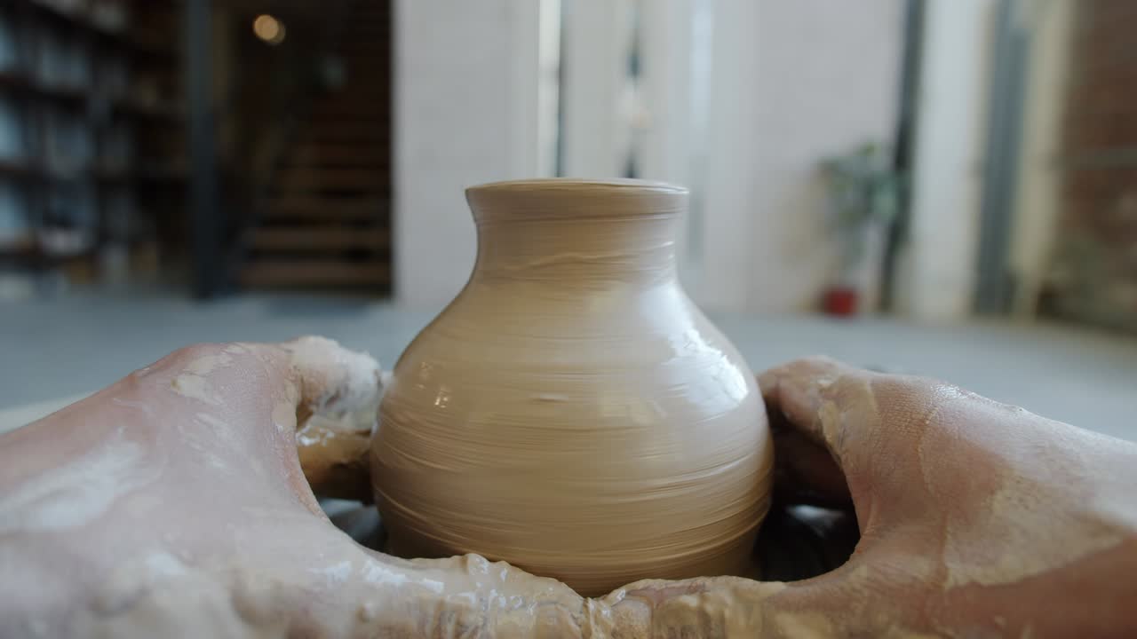 Cinemagraph loop of beautiful vase made of clay rotating in craftsman's hands in workshop