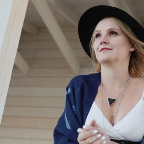 retrato de una mujer elegante con sombrero y poncho en una veranda 1