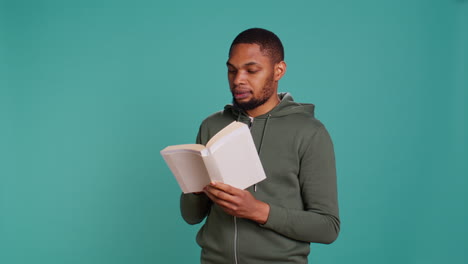 Man-laughing-while-reading-funny-book,-entertained-by-story