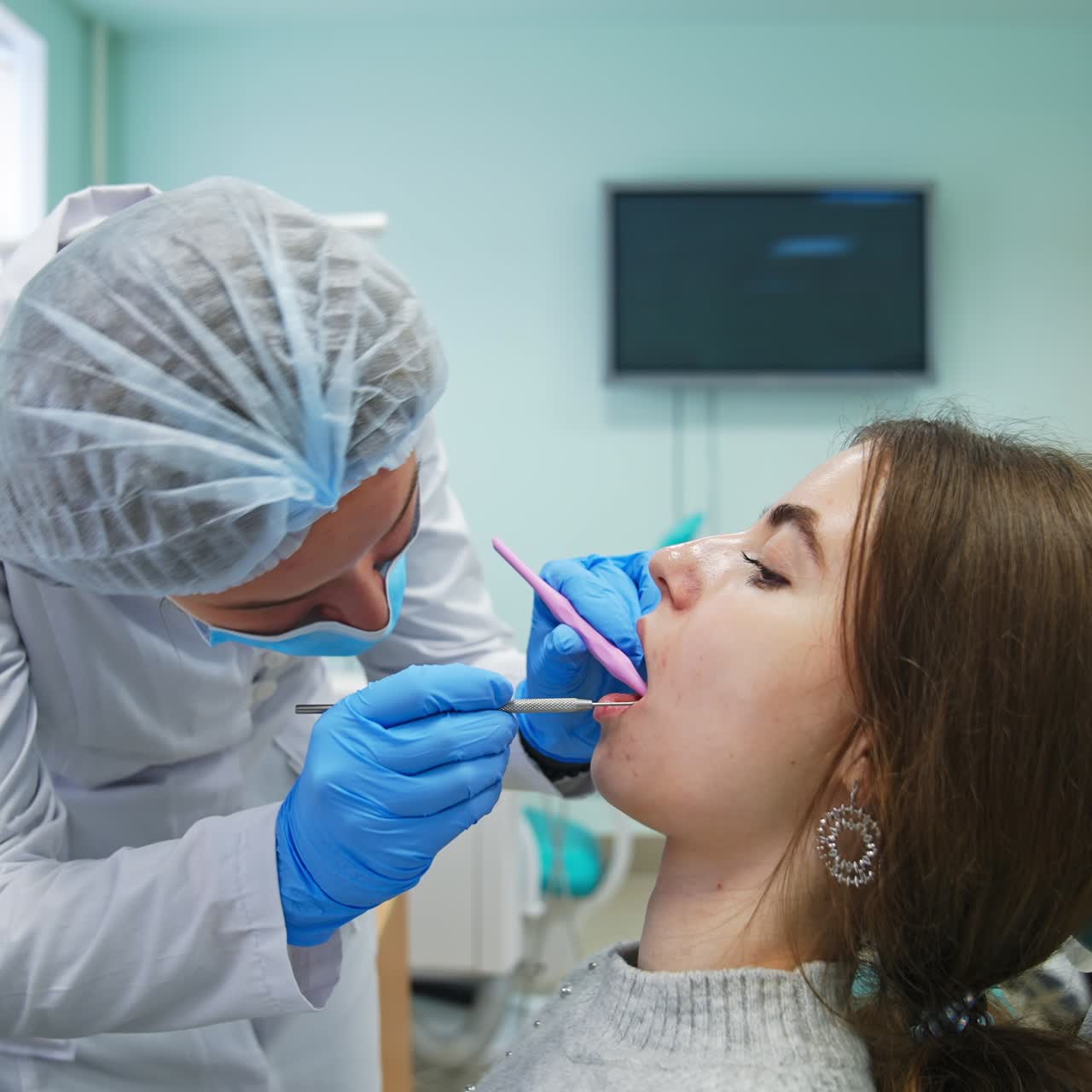 Student checking lower row of teeth with medical instruments. Professional dentist teaching student
