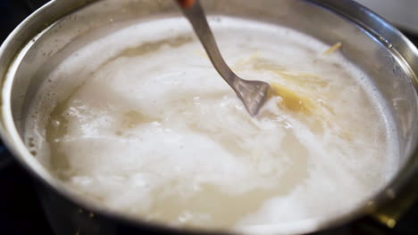 cook stirring a boiling pot full of spaghetti noodels in slow motion