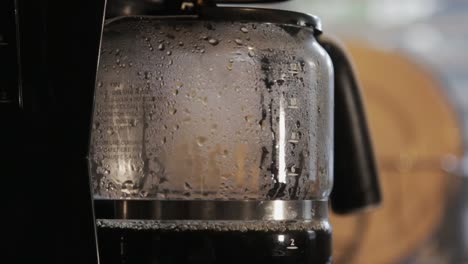 brewing coffee liquid dripping from a filter inside a coffee maker- close up shot