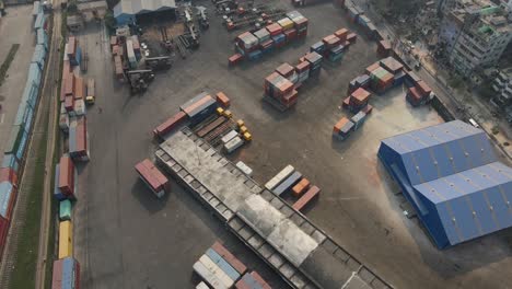 aerial: inland shipping container terminal with warehouse inside city- drone flight shot