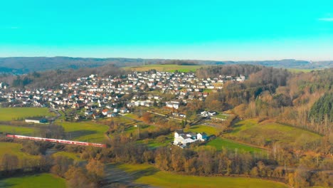 vuelo de drones sobre un pequeño pueblo con un tren de pasajeros pasando