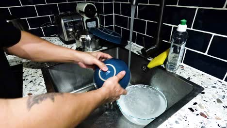 person washing a blue dish in sink