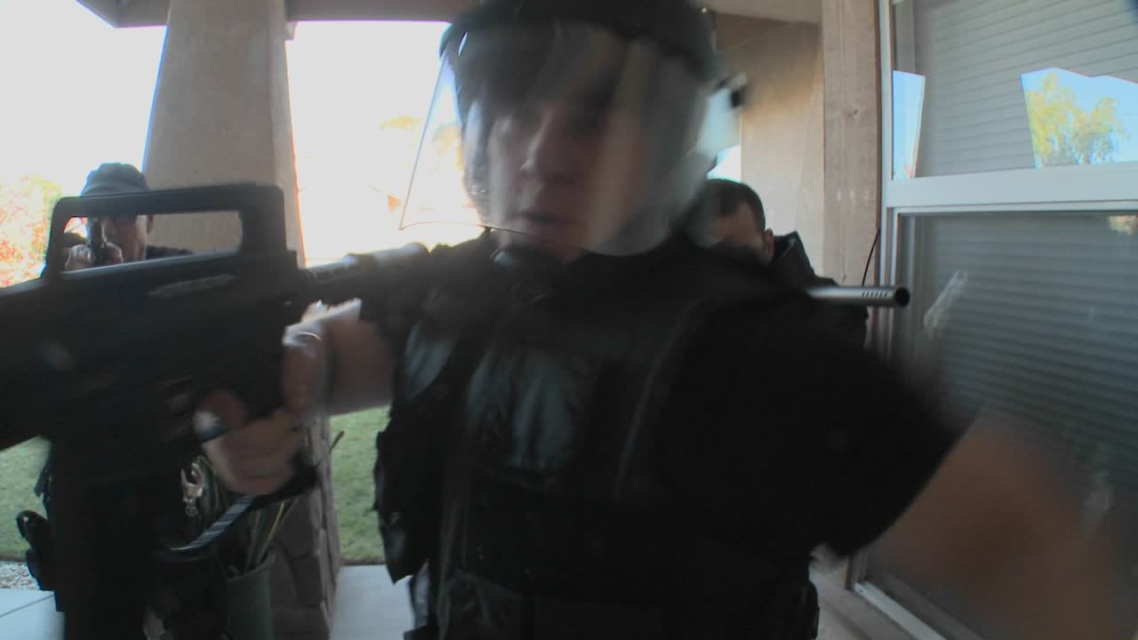 oficiales de la dea o swat con los brazos en alto golpean la puerta antes de realizar un allanamiento de drogas en una casa