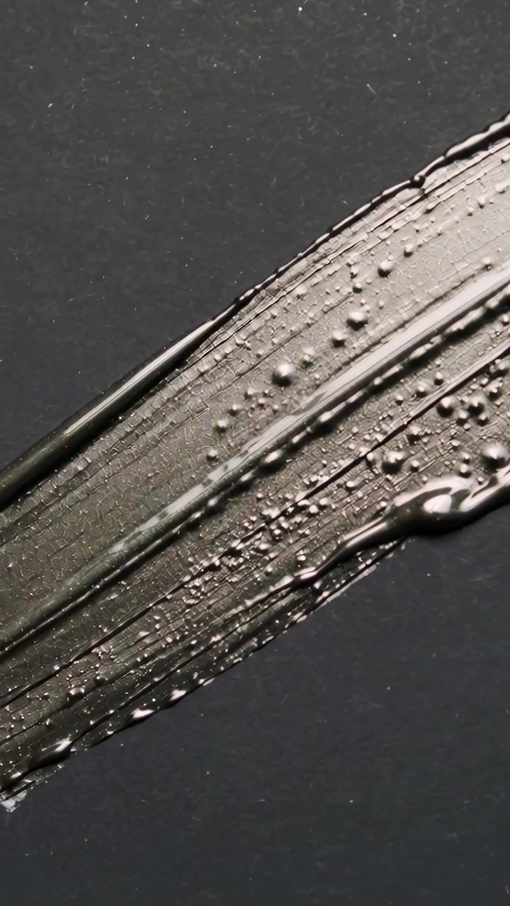 Vertical video: Tapping fingertip dragging dark pigment across matte black card revealing texture