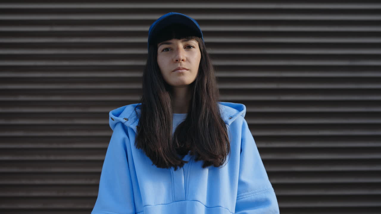 Portrait of a young woman in a blue hoodie and baseball cap