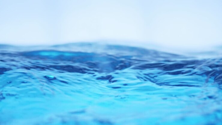 La superficie dell'acqua pulita al rallentatore riempie lo schermo, mostrando schizzi d'acqua, una goccia d'acqua e una superficie liquida ondeggiante con una bolla d'aria.