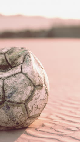 old soccer ball on a beach at sunset