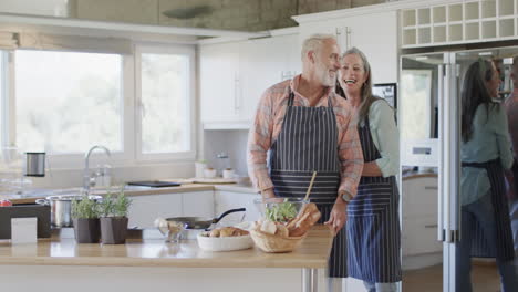 Pareja-Caucásica-De-Mediana-Edad-Poniendo-Delantal,-Cocinando-En-La-Cocina-De-Casa,-Cámara-Lenta