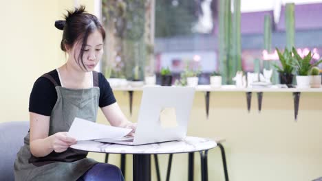 the restaurant manager is surfing the web and communicating. sitting in a coffee cafe, looking over documents.