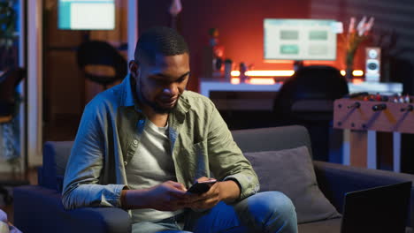 vertical video african american person texting messages on a smartphone app on the sofa
