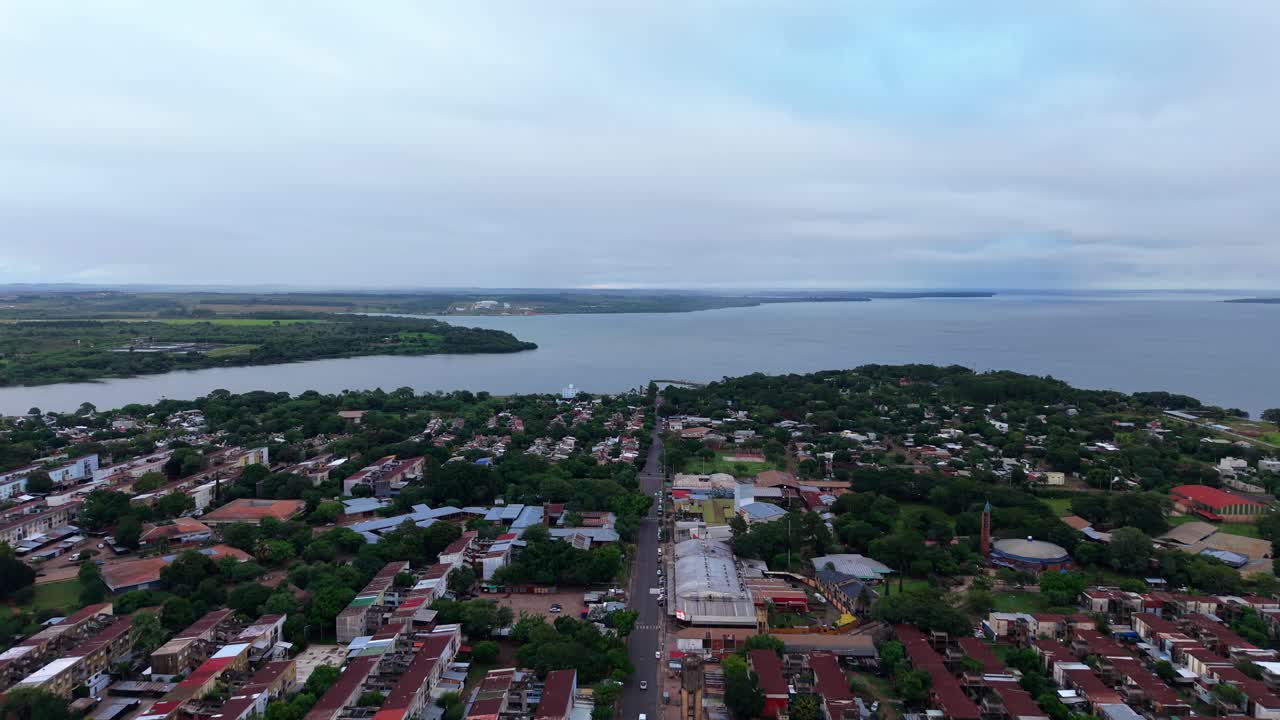 Un volo drone fluido in avanti sopra Villa Cabello verso il vasto orizzonte del fiume Paraná.