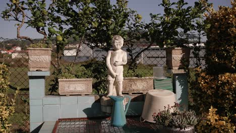 stone pissing boy statue in a garden with potted plants and vintage elements