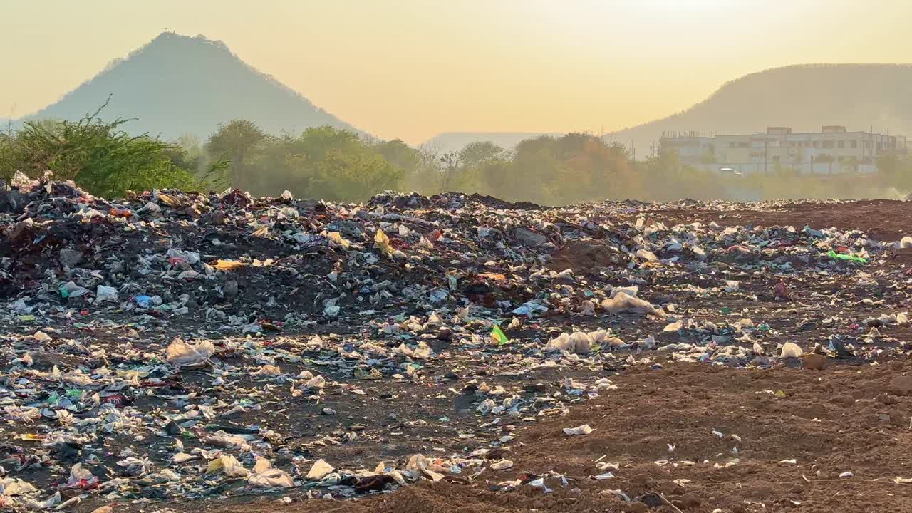 static shot of a land filled with wasted plastic bag creating microplastic pollution and burning the garbage creating the air pollution