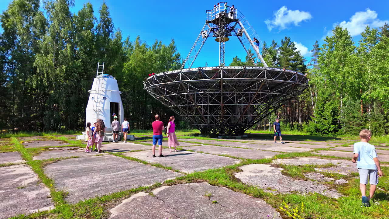 People visiting a large radio telescope in a forest