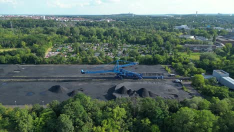 spreader reclaiming coal excavator at a coal terminal near residential area. dramatic aerial view flight fly reverse drone