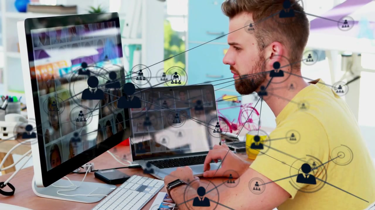 Mand bruger mus ved skrivebord, klikker for at visualisere netværksikoner, der spreder sig over skærm, bærbar computer og manden.