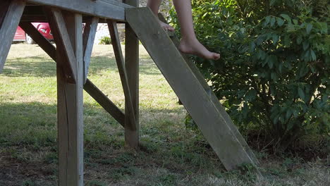 child carefully steps down small ladder from play structure