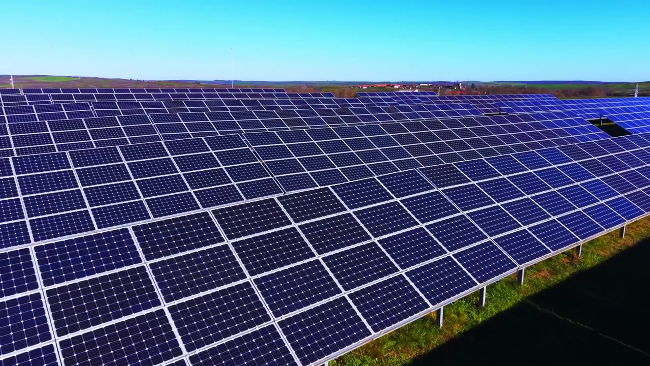 Ampia vista panoramica dal basso di un grande parco infrastrutturale pulito che genera energia verde. Vasta schiera di pannelli solari a inseguimento solare sotto un cielo blu.