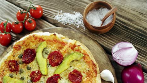 italian pizza on wooden table with vegetables and spices