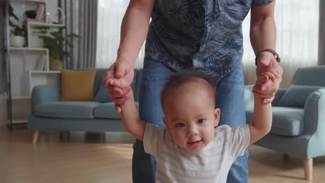 Father Encouraging Smiling Baby Son Walk At Home